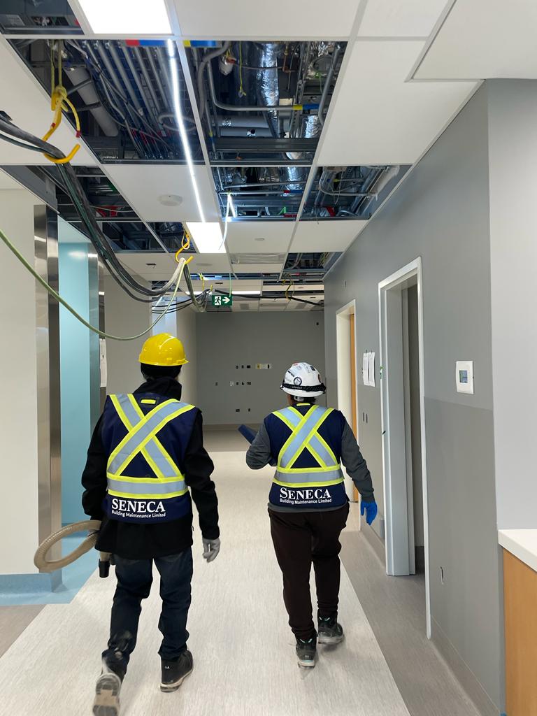 Two workers providing services, walking down a hallway in a hospital.
